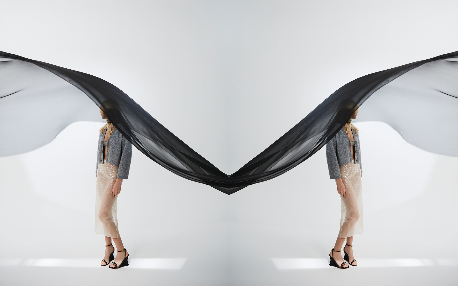 Woman in black satin evening wedge sandal on flowing silk backdrop — handcrafted resort wedge by Sitrène. Black satin evening wedge on marble.